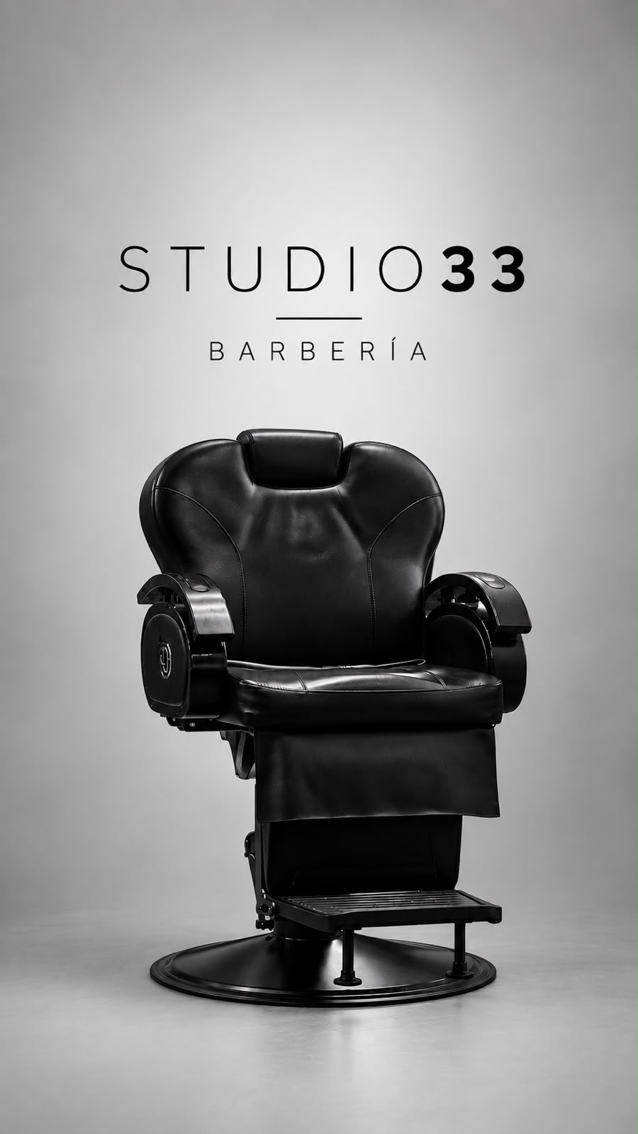 Sillón de barbería negro frente al logo Studio 33 Barbería